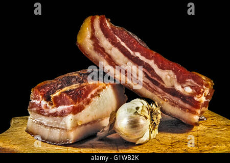 Domestic bacon and garlic on wooden kitchen board. Stock Photo