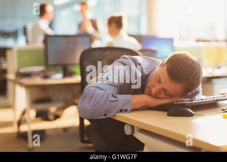 Businessman sleeping on desk in office Stock Photo