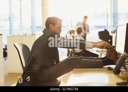 Businessman stretching feet on desk in office Stock Photo