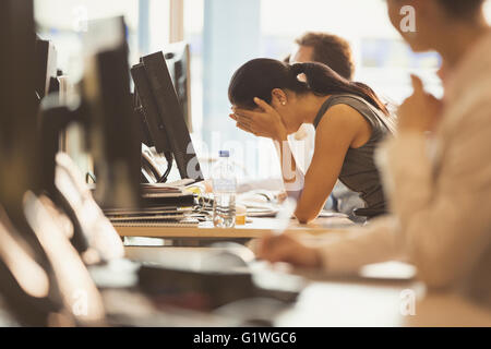 Stressed businesswoman with head in hands at office desk Stock Photo