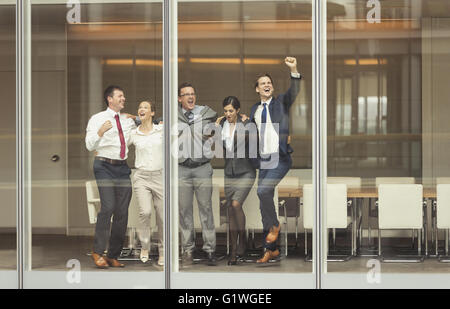 Business people celebrating and cheering at conference room window Stock Photo