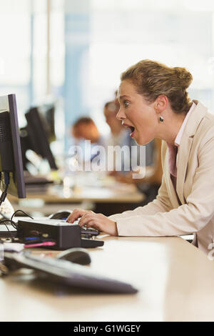 Shocked businesswoman working at computer in office Stock Photo