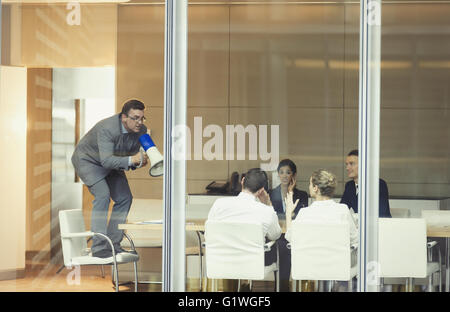 Businessman with megaphone on top of chair in conference room meeting Stock Photo