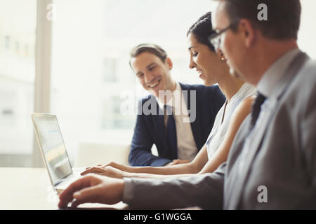 Smiling business people using laptop in conference room Stock Photo