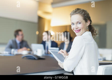 Portrait smiling businesswoman using digital tablet in conference room meeting Stock Photo