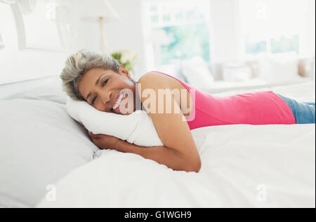 Portrait smiling mature woman laying on bed Stock Photo
