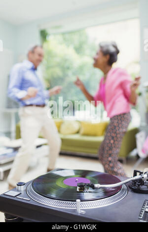 Playful nature couple dancing in living room behind record player Stock Photo