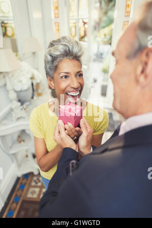 Surprised mature woman receiving gift from husband Stock Photo