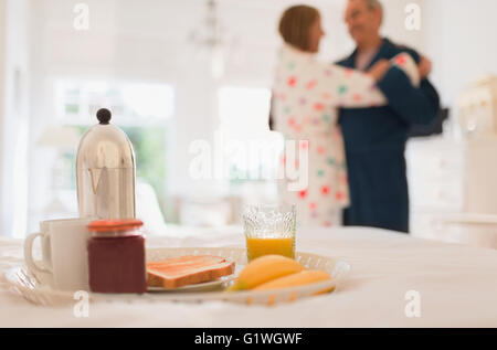 Mature couple in bathrobes dancing behind breakfast in bed Stock Photo