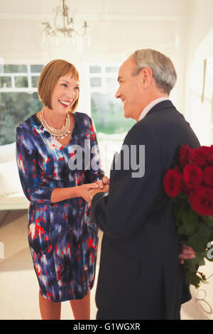 Well-dressed husband surprising wife with rose bouquet Stock Photo