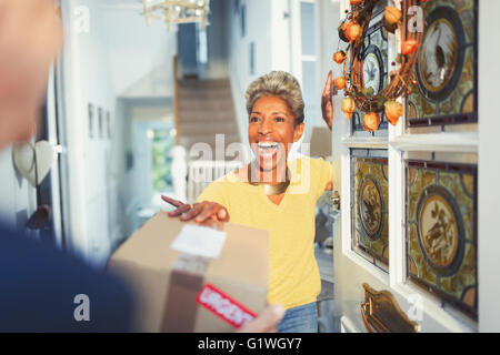 Enthusiastic woman receiving package delivery at front door Stock Photo