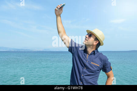 Man Taking A Selfie With His Smart Phone On The Beach Stock Photo