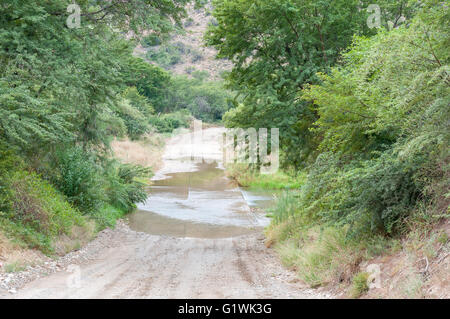 The road through the Baviaanskloof (baboon valley) crosses the Baviaans River on a concrete causeway, one of many such crossings Stock Photo