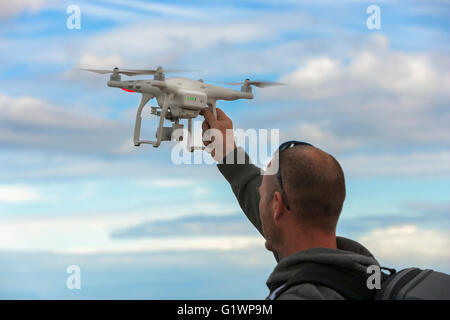 Man retrieving his Phantom Pro 3 drone and camera hovering in sky-Victoria, British Columbia, Canada. Stock Photo