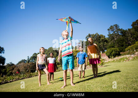 Kids playing together during a sunny day with a kite Stock Photo