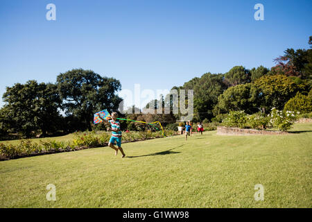 Kids playing together during a sunny day with a kite Stock Photo