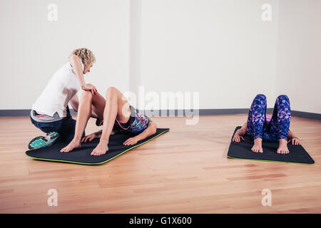 A therapist is correcting the technique of women exercising and stretching in a gym Stock Photo