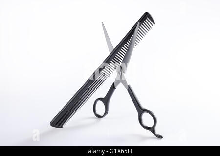 Barber scissors and comb standing on a white table, overview isolated Stock Photo