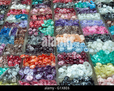 Various colorful buttons in plastic box for sell, focus on the center of image. Stock Photo