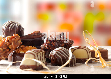 Group of bonbons stacked. Black and white chocolate with nuts and straw decoration on a table with brown tablecloth fabric Stock Photo