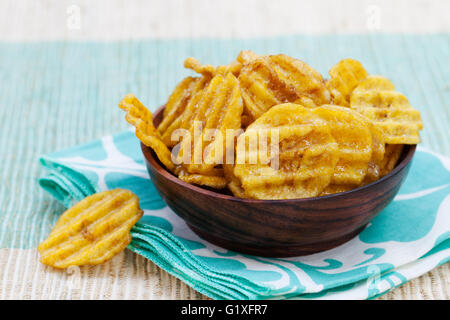 Dried dehydrated deep fried banana chips in a wooden bowl Stock Photo