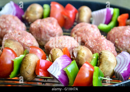 Vegetables skewer and lamb meatballs, raw, on the grill Stock Photo