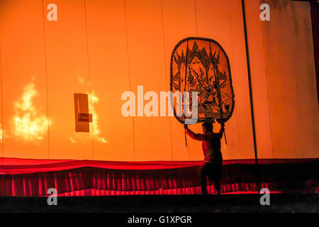 RATCHABURI THAILAND - APRIL 14, 2015: The Cowskin shows a man holding a stencil pattern. Moving Cowskin the light to shadow play Stock Photo