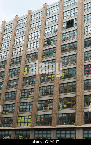 Colourful pixel art made from sticky notes by employees in the windows of rival office buildings on Canal Street, New York City Stock Photo