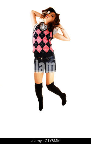A tall young chinese woman in a vest and jeans shorts and long black boots is jumping for white background. Stock Photo