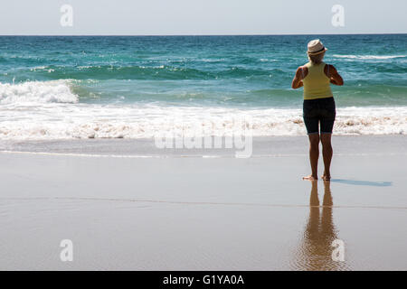 Woman standing on beach looking at the Pacific Ocean on the Gold Coast in Queensland Australia Stock Photo