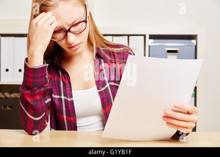 Woman looks worried at the bill on her hands Stock Photo