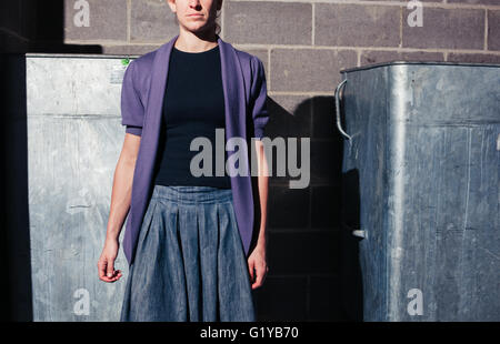 A young woman is standing next to two large bins in a basement Stock Photo