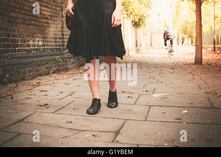 The legs of a young woman as she is walking in an alley on a sunny day Stock Photo