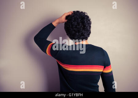 A young man is scratching his head in confusion Stock Photo