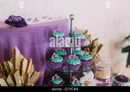 Set of different delicious lavender cakes cupcakes on funny cake-stand, violet backgraund Stock Photo