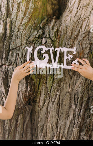 Vintage wooden inscription Love and hands of just married couple, tree on background Stock Photo