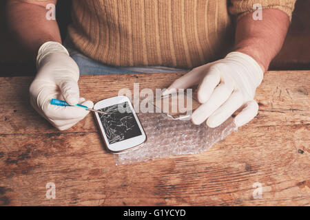 A technician is fixing and replacing the broken screen on a smart phone Stock Photo