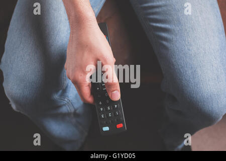 A male hand is holding and pointing a remote control Stock Photo