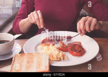 A woman is having a traditional english  breakfast in a cafe Stock Photo