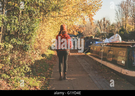 A young woman wearing winter clothes and hat is walking by the canal Stock Photo
