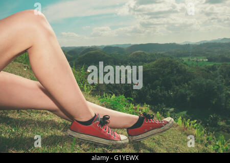 The legs of a young woman as she is relaxing on a hill in the tropics Stock Photo