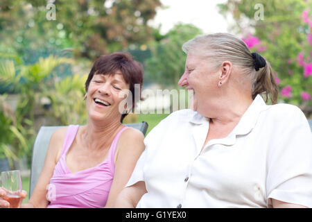 Two middle aged women laughing having fun in garden Stock Photo