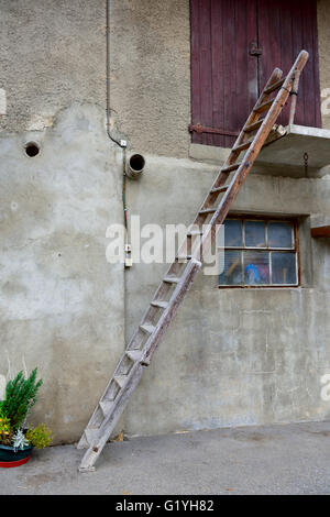 Wooden ladder resting against barn Stock Photo