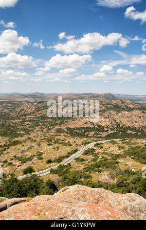 Mountain road winding through an arid landscape between outcrops of rock at Wichita Mountains Stock Photo