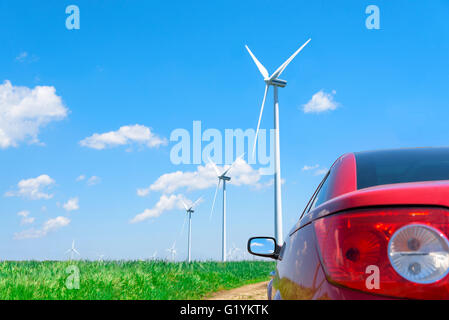 Red car and wind turbines generating electricity. Stock Photo