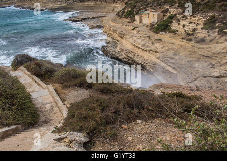 Rocks on the coast of Mediterranean sea, south-east of island Malta. Blue water of the sea, white waves, breaking at the rocks o Stock Photo