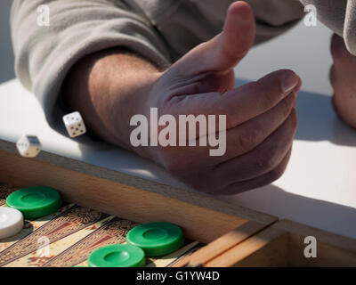 Close-up of person's hand throwing dice playing backgammon Stock Photo