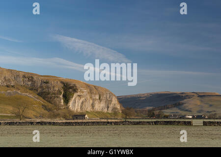 Scenic Wharfe Valley (rolling hills & moors, sunlit high limestone cliff (Kilnsey Crag) & deep blue sky - Wharfedale, Yorkshire Dales, England, UK.