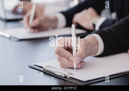 Business people making notes sitting in a row at conference Stock Photo