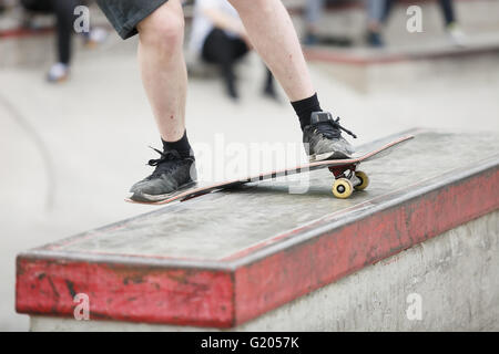 Skater boy grinding on a ledge in outdoor skate park. Popular extreme sport, dangerous, fun. Focus on skateboard Stock Photo